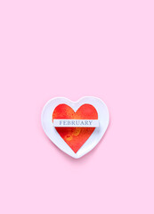 heart and calendar block with text "February" in plate on pink background. love heart, romantic symbol. festive card, minimal creative idea. Valentine's day, 14 February holiday concept. flat lay