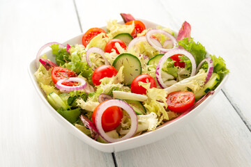 Piatto di insalata fresca vegana con lattuga, cetriolo, pomodoro, cipolla, olio di oliva e origano 