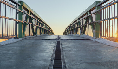 concrete pedestrian bridge with iron railings in sunset. winter