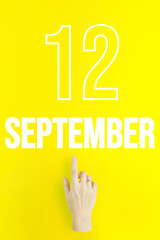 September 12nd. Day 12 of month, Calendar date.Hand finger pointing at a calendar date on yellow background.Autumn month, day of the year concept.