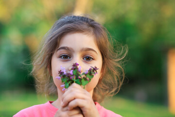 Little cute girl with pinc flowers. Child  playing in summer garden. Kids gardening. Children play outdoors. Toddler kid with flower bouquet for birthday or mother s day.