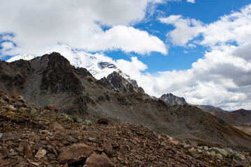 Mountain view at a very high altitude. Picturesque alpine landscape with beautiful sharp cliffs and glaciers in sunlight against a deep blue sky.