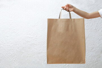 Close up cropped child hold brown empty blank paper bag for takeaway isolated on white background background