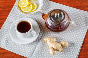Cup and teapot of hibiscus tea and hibiscus petals on a white background.