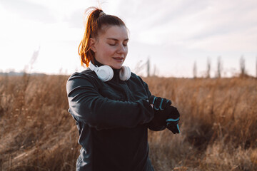 Athletic female using fitness tracker or smart watch between run training outdoors, checking heart rate banner