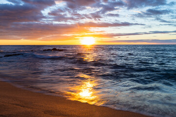 A gorgeous sunset with the sun on the horizon of a beautiful beach. 
