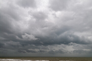 Obraz premium View over the sea to dramatic looking storm clouds. Dark dramatic lonely sea landscape. 