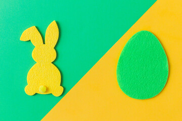 Colorful Easter egg and bunny on green and yellow background, flat lay with space for text. Happy Easter! Green and yellow artificial egg and bunny decor. Creative Easter hunt concept