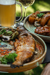 Glass of light foam beer and white wine with grilled fish and meat.
