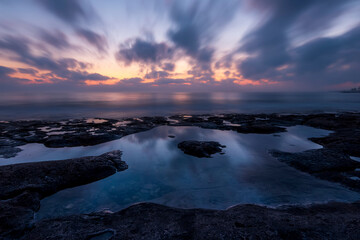Twilight scenic sea landscape with beautiful shore, blurred flying dramatic blue clouds, amazing shoreline and sunset on background