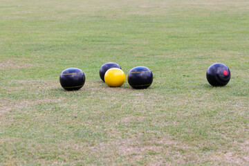 Crown green bowling balls gathered close to the yellow Jack as the players compete to get closest...