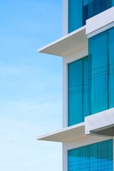 Side view of blue roller blinds inside of glass wall of modern office building against blue sky in vertical frame