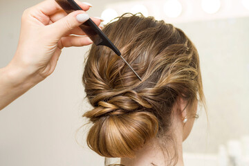 Naklejka premium The stylist performs the hairstyle, hair styling in the salon.