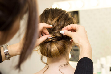 Naklejka premium The stylist performs the hairstyle, hair styling in the salon.