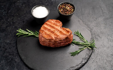 Fototapeta na wymiar Heart shaped grilled beef steak with arrow for valentine's day on stone background