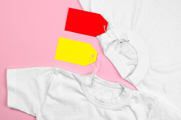 Two white T-shirts on a pink background with blank price tags. Blank label on clothes