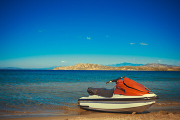 Water scooter on the beach in the bay, blue sky, mountains in the background. Wide angle, Copy...