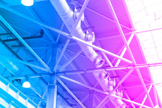 Blue Lights and ventilation system in long line on ceiling of the  industrial building. Exhibition Hall. Ceiling factory construction in blue and pink tones
