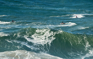 Surfing waves in the Atlantic Ocean in Nazaré, Portugal