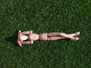 Wooden doll lying on the grass relaxed sunbathing