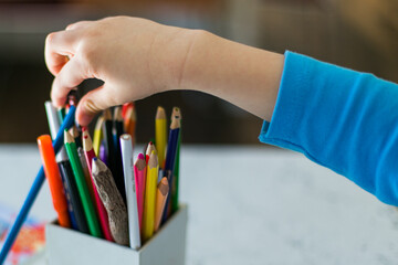 child in the blue pajamas writing or drawing something with colorful pencils
