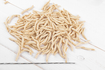Whole grain wheat raw apulian pasta called Pizzarieddi or maccaruni on a on white wooden table....