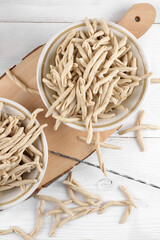 Whole grain wheat raw apulian pasta called Pizzarieddi or maccaruni on a ceramic plate on white...
