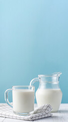 A jug and a glass of fresh milk on a blue background.