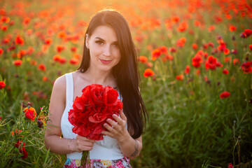 Fototapeta premium beautiful girl in a poppy field at sunset