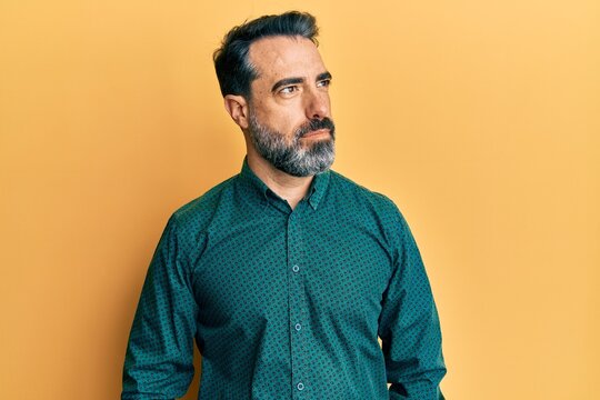 Middle age man with beard and grey hair wearing business clothes smiling looking to the side and staring away thinking.