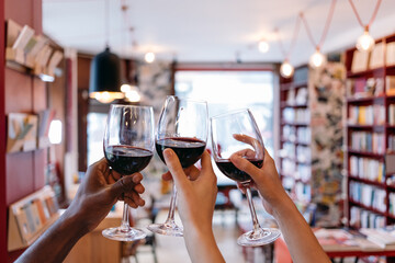 toasting raised hands holding glasses in a book cafe - celebration