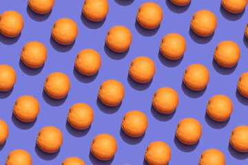 Fruit oranges in checkered pattern on violet background. Violet and orange colors background from fruity oranges. Demonstrating very peri, color of 2022 year.