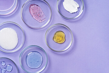 Cosmetic products, scrub, face serum and gel in many petri dishes on a pink background. Cosmetics...