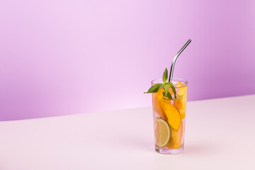 Refreshing summer drink. Peach juice or cocktail with peach slice, ice cube and mint on abstract white and pink background.