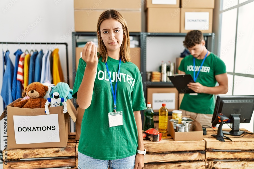 Poster Young blonde girl wearing volunteer t shirt at donation stand doing italian gesture with hand and fingers confident expression