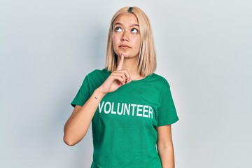 Beautiful blonde woman wearing volunteer t shirt thinking concentrated about doubt with finger on...