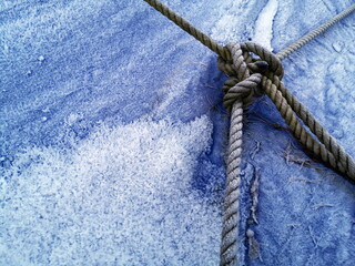 Schiffstau mit Knoten auf einer vereisten blauen Plane über einem Bootsanhänger im Winter in...