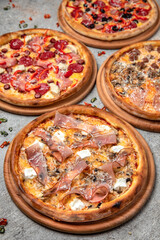 Pizza party dinner. Flat-lay of different kinds of Tasty hot Italian pizza on a beige textured background. Fast food lunch, gathering, celebration. Pizzeria 
