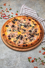Tasty hot italian pizza with Mozzarella, Ham, mushrooms, olives and Tomato Sauce on a beige textured background. Pizzeria menu. 