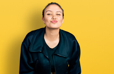 Young hispanic girl wearing sportswear looking at the camera blowing a kiss on air being lovely and...