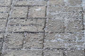 De-icing chemicals reagent on asphalt. Pavement is sprinkled with technical salt or salt mixtures based on it. Effective tool to fight ice on roads in winter season. . 