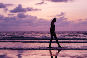 Young slim woman silhouette walking on horizon background.