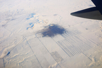 View to the wing of airplane in the sky and snowy mountains. Travel and transportation concept