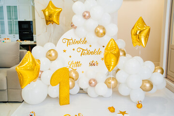 A photo zone for the first birthday of white and gold balloons and a figure one 