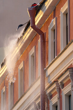 Cropped Photo Of Man Homeowner Removing Clearing Snow From Edge Of Roof On Winter Day, Qualified Professional Holding Shovel Cleaning Rooftop From Ice And Icicles During Wintertime. Ice Dam Prevention