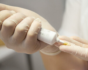 Cosmetologist hold anti ageing cream tube for applying facial mask or scrub aha acids. Acne treatment for face. Skincare spa procedure tools close up.