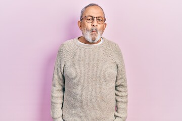 Handsome senior man with beard wearing casual sweater and glasses making fish face with lips, crazy and comical gesture. funny expression.