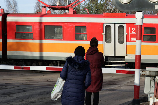 Przejazd kolejowy w dużym mieście z zamknietymi szlabanami. 