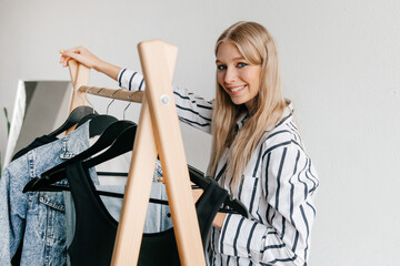 Happy smiling young woman choosing clothes from her personal wardrobe