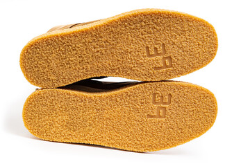 non-slip outsoles of two brown leather winter boots on a white background